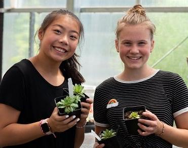 Two students hold plants at 技术中心 course